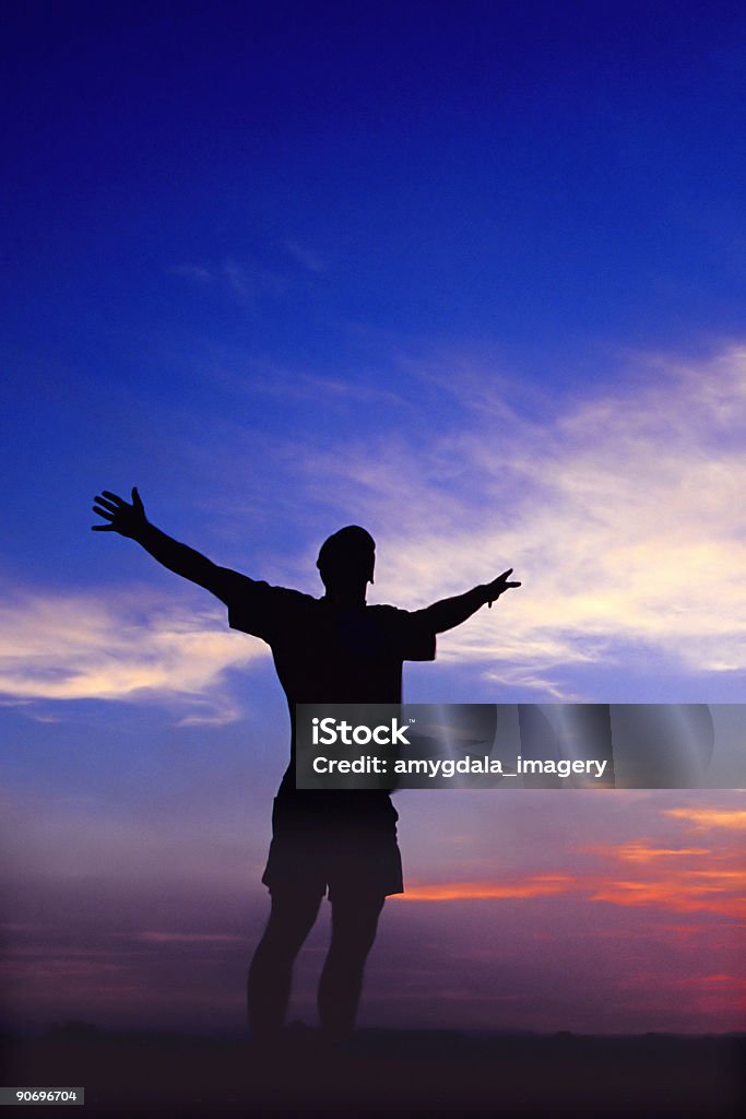 silhouette uomo con le braccia sollevate al cielo al tramonto - Foto stock royalty-free di Inquadratura dal basso