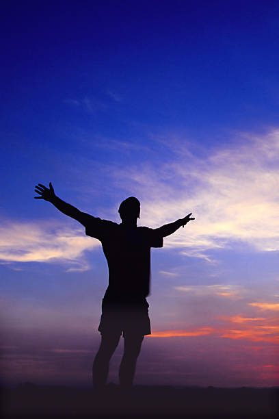 istock silhouette man arms raised into sunset sky 90696704