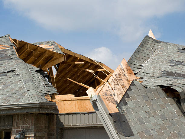 Roof of a residential house showing damage to the tile and gutter systems, multiple layers of shingles, missing shingles, and rusty gutters.