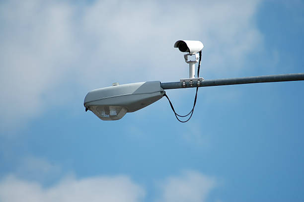 A camera installed on a streetlight watches traffic stock photo