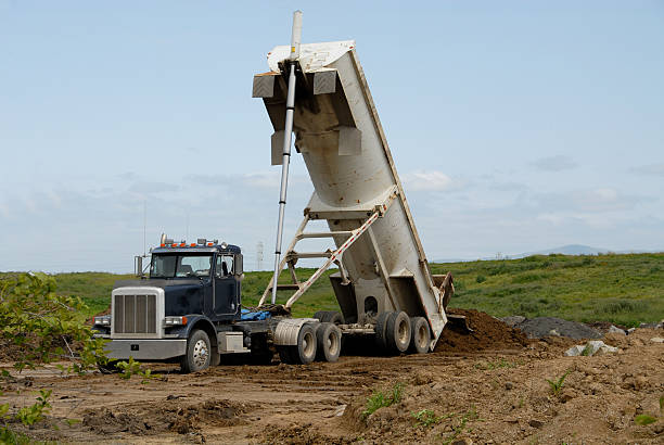 Dump truck dumping dirt into a field stock photo