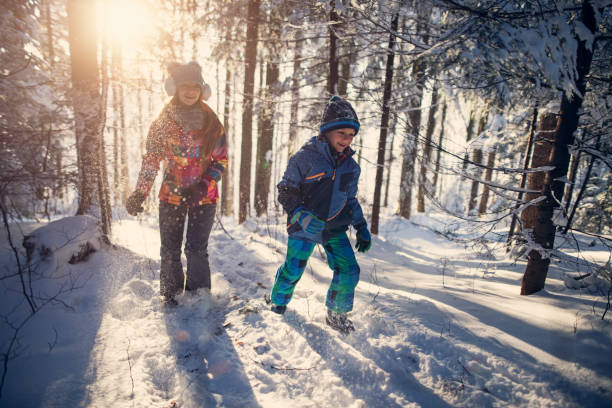 istock Brother and sister running in sunny winter forest 907011852