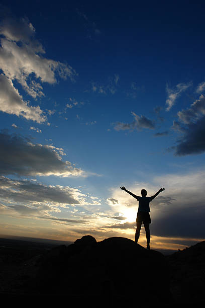 istock silhouette woman arms raised into sunset sky landscape 90701878