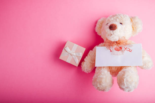 istock Teddy bear with a gift box for Valentines day on pink background 907021198
