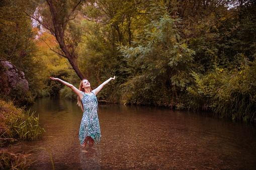 Happy woman with raised arms enjoying life in nature