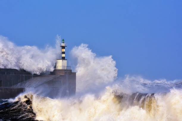 Stormy wave over lighthouse and pier of San Esteban de Pravia
