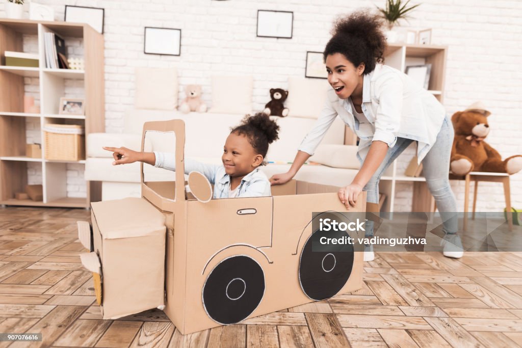 Mãe e filha estão jogando com carros de brinquedo grande. - Foto de stock de Carro royalty-free