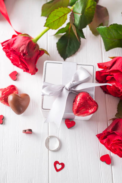 istock Fresh red roses and gift box on wooden table 907095466