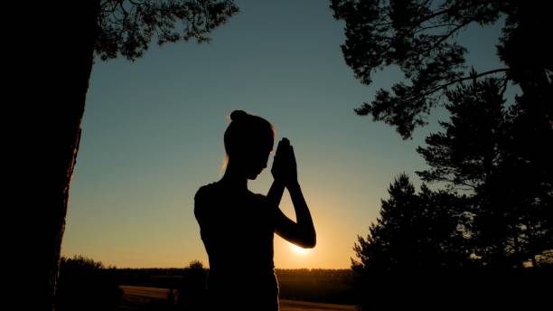 deportiva mujer rezando en el parque al atardecer - praying forest freedom tree fotografías e imágenes de stock