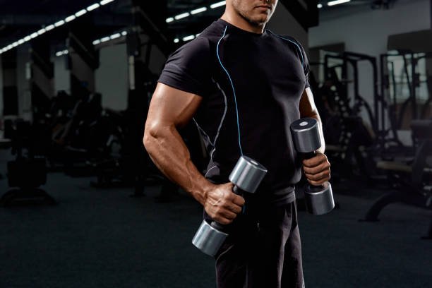 istock Muscular bodybuilder doing exercises with dumbbell in gym.Strong athletic man shows body,abdominal muscles,biceps and triceps.Work out,gaining weight,pumping up muscles with dumbbells. 907137514
