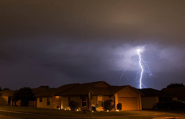 Lightning strikes in the night near family houses stock photo