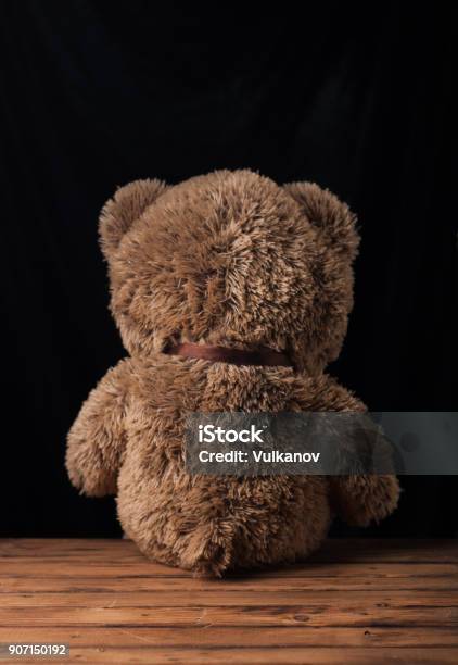 A Lone Teddy Bear Sits On A Wooden Surface Stock Photo - Download Image Now - Abandoned, Back, Belarus