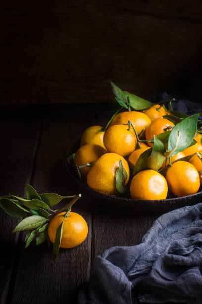 istock Tangerines with leaves on dark wooden table. 907155428