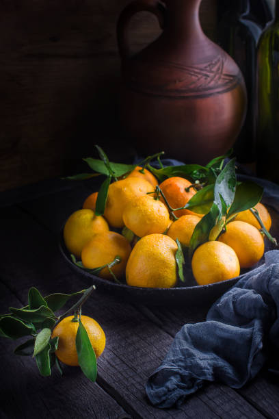 istock Tangerines with leaves on dark wooden table. 907156438