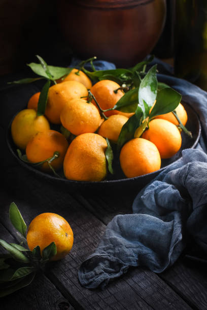 istock Tangerines with leaves on dark wooden table. 907157032