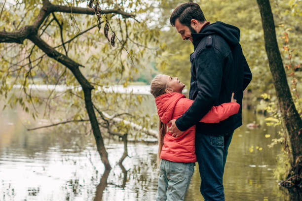 istock father and daughter near lake 907157534