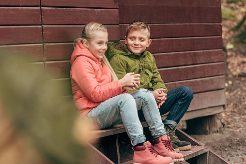 beautiful happy little kids sitting together on wooden stairs