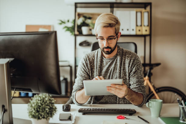 istock Young hipster using his digital tablet in the office during morning hours 907175208