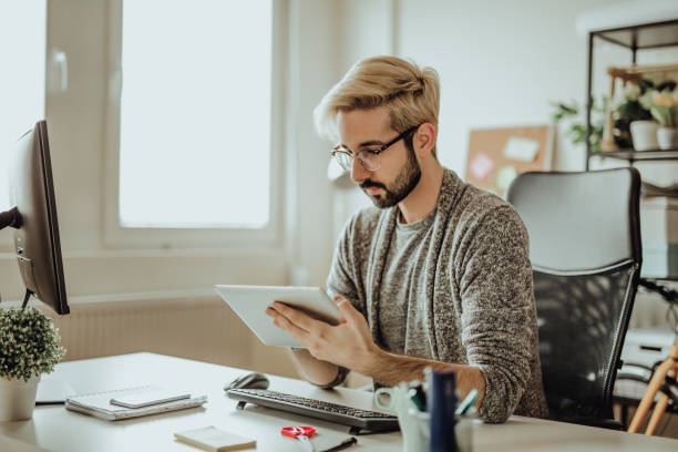 istock Young hipster using his digital tablet in the office during morning hours 907175494