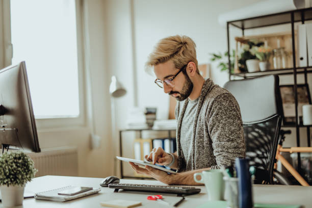istock Young hipster using his digital tablet in the office during morning hours 907179094