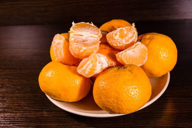 istock Plate with mandarins on a dark wooden table 907191520
