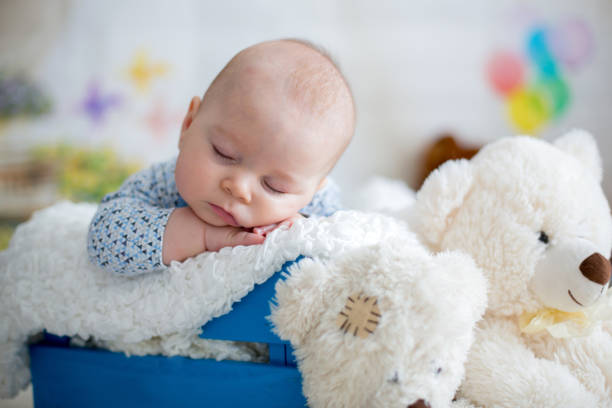 istock Little baby boy with knitted hat, sleeping with cute teddy bear 907201882