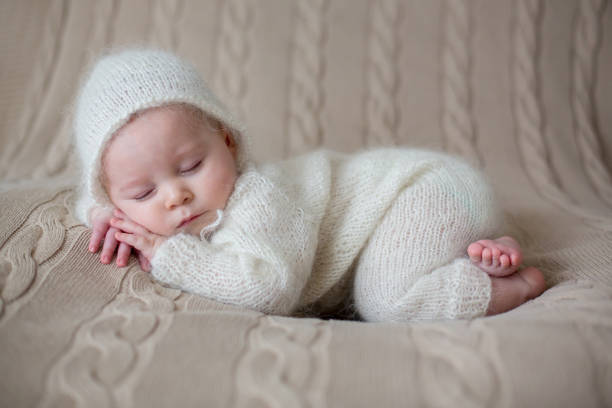 istock Beatiful baby boy in white knitted cloths and hat, sleeping 907208714