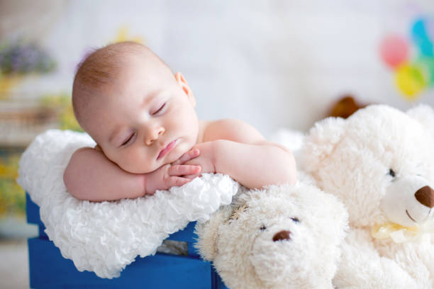 bambino con cappello a maglia, che dorme con un simpatico orsacchiotto - baby sleeping bedding teddy bear foto e immagini stock