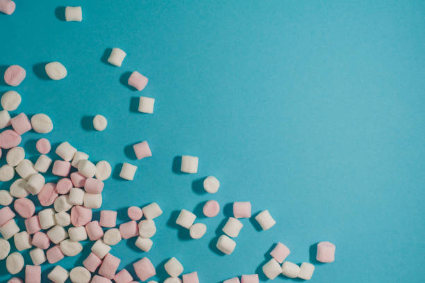 istock White and pink marshmallows on a blue background. Place for text 907248714