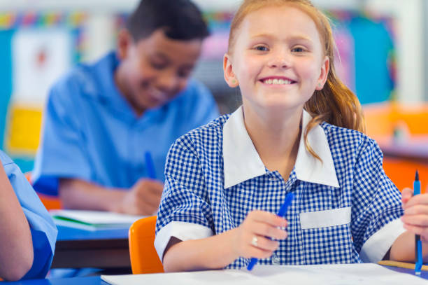 istock Young schoolgirl smiling in class. 907283204