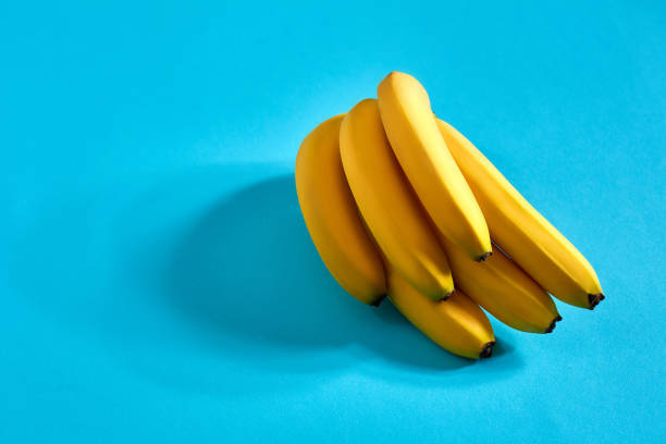 istock Yellow ripe bananas on blue background with space for text or design. Top view 907311976
