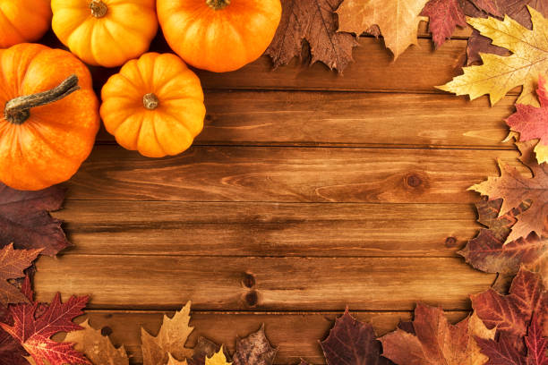 istock Pumpkins with fall leaves over wooden background. 907332632