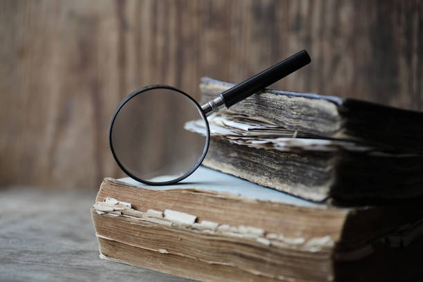 istock Old books on a wooden table and magnifier 907354992