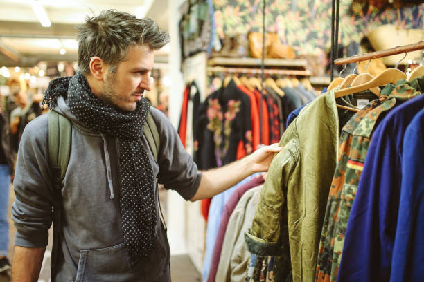 istock Young man trying out clothes in London second hand market 907365828