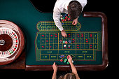 Man croupier and woman playing roulette at the table in the casino. Top view at a roulette green table with a tape measure