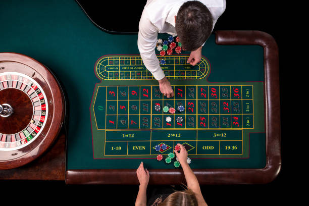 мужчина крупье и женщина играют в рулетку за столом в казино. вид сверху на зеленом столе рулетки с рулеткой - roulette table стоковые фото и изображения