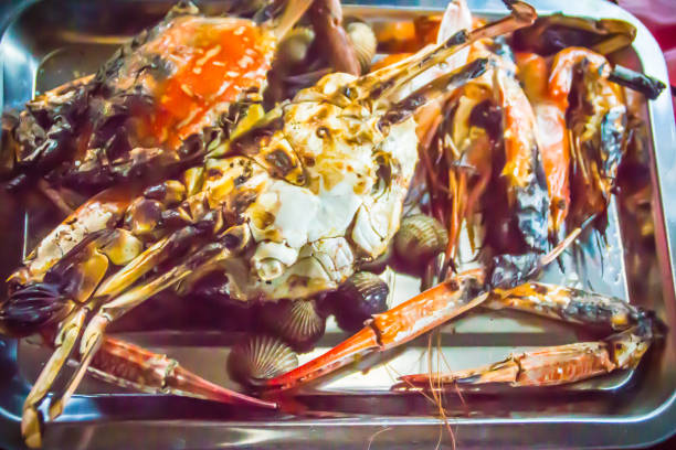 Close up grilled crabs and clams on fire charcoal stove at night party. Seafood barbecue party with crabs and clams are grilling on fire. Seafood BBQ concept, selective focus. cerca de cangrejos a la plancha y almejas en fuego de carbón de leña de la estufa en la fiesta de la noche. fiesta de barbacoa de mariscos con cangrejos y almejas están asando en el fuego. concepto de barbacoa de mariscos, enfoque selectivo.