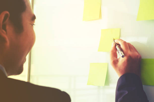 istock Businessman putting his ideas in Post-it planning on new business project 907389060