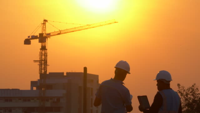 Inspecting Engineer in Construction Site at Sunset