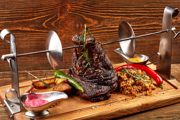 istock Roasted pork knuckle eisbein with braised boiled cabbage, potatoes, chili peppers and mustard on wooden cutting board 907396402