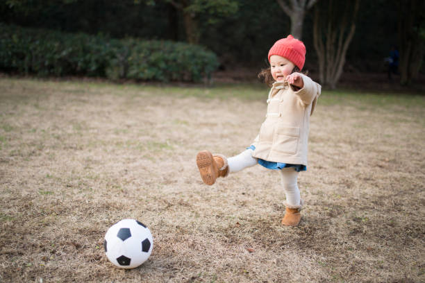 Little girl kicking a soccer ball Little girl is kicking a soccer ball in a winter park toddler hitting stock pictures, royalty-free photos & images