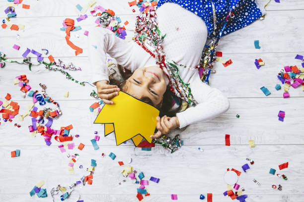 pequena menina bonita e bela com confete colorida no chão feliz é feliz em uma princesa de coroa de papel - coroa enfeites para a cabeça - fotografias e filmes do acervo