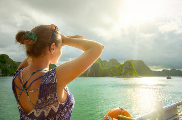 woman traveler on the boat, enjoying view of the island at sunset - halong bay vietnam bay cruise imagens e fotografias de stock