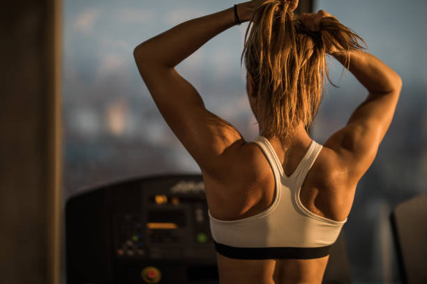 vista posterior de mujer atlética hacer cola de caballo antes de entrenamiento en un gimnasio deportivo. - ponytail hairstyle female back fotografías e imágenes de stock