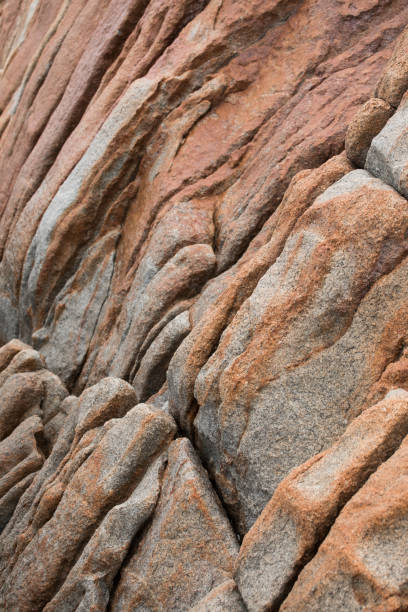 istock Rock on the beach - red colored stone texture close-up 907482702