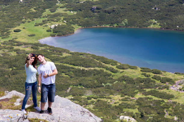 istock couple  on mountain peak taking picture 907484910