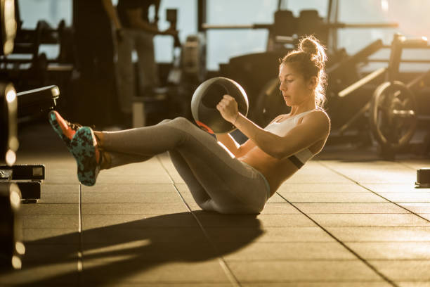 desportista, fazer abdominais com bola medicinal em formação em um ginásio de esportes. - sit ups - fotografias e filmes do acervo