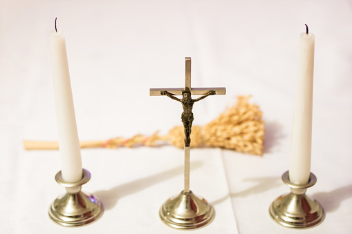 Cross and candles on a white tablecloth. Carol singing, cross and candles on a white table. Holiday time.