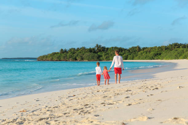 istock father and two kids walking on beach 907490712