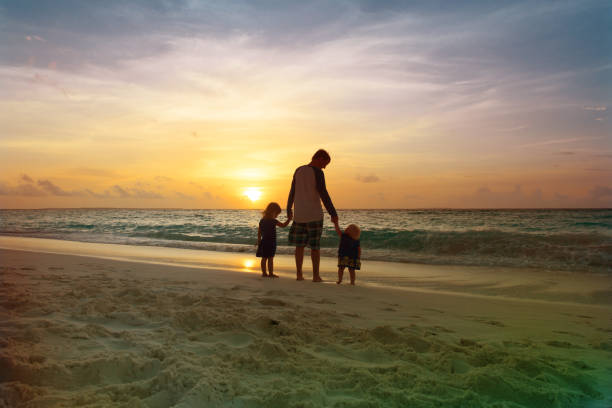 istock father with kids walk on beach at sunset 907491164